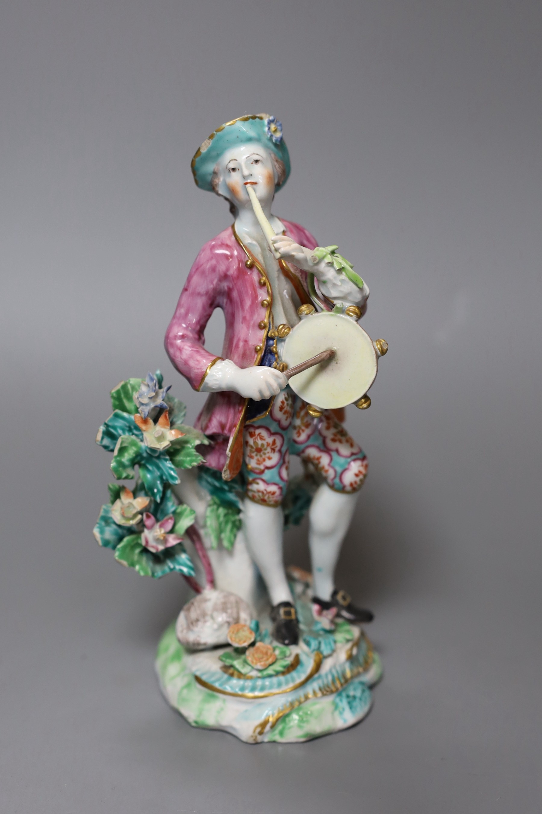 A Bow figure of a young man blowing a pipe and beating a tabor, 20cm tall